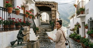 Callejón tradicional con tinao de madera y estatua de la bruja en la fuente del pueblo de Soportújar